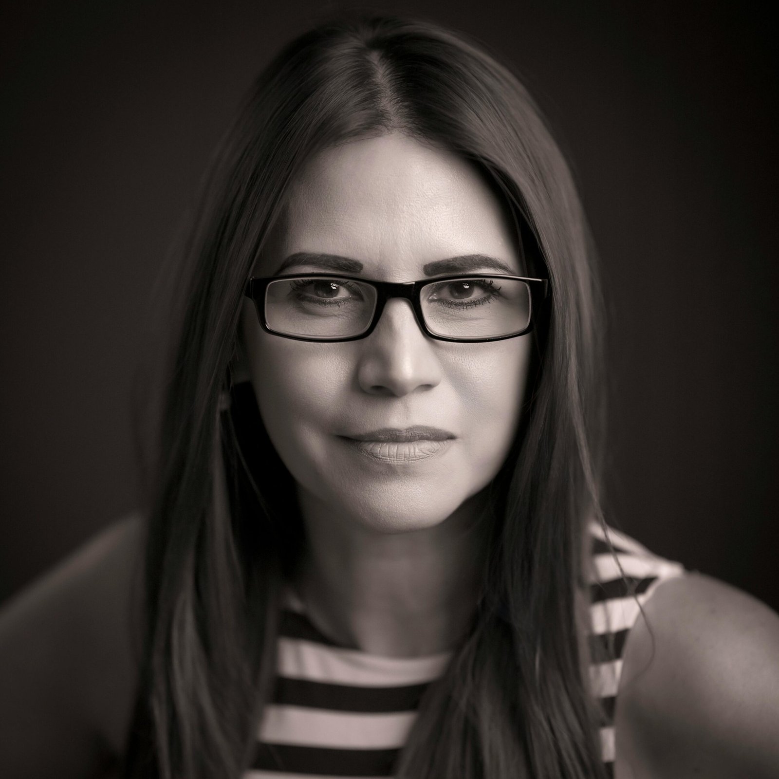 Home Portrait of a professional woman with glasses, emphasizing a confident and intelligent expression.